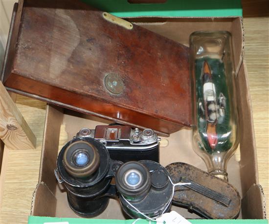 A pair of binoculars, set of scales and a ship in a bottle